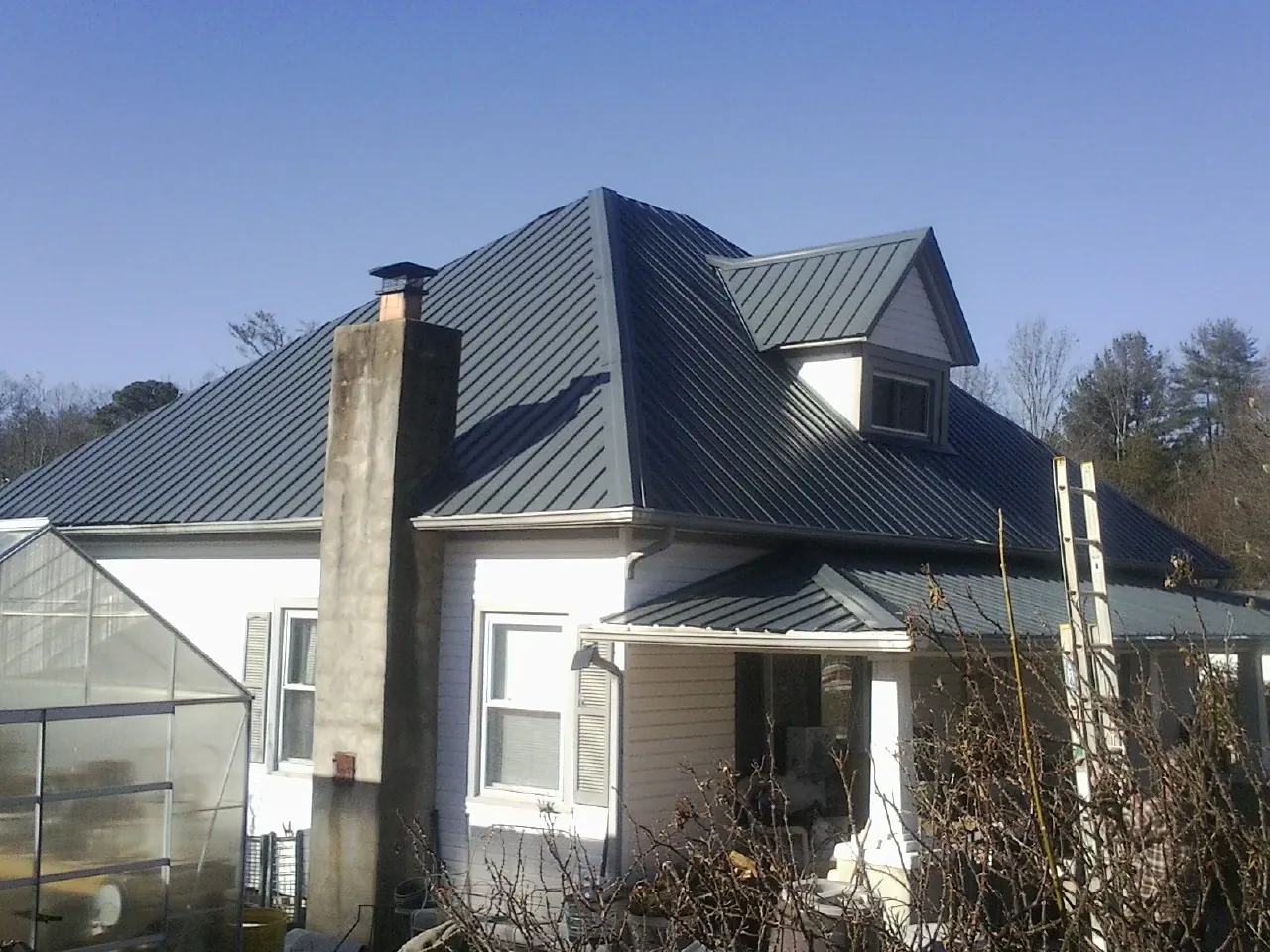 Dark blue standing seam metal roof on a white farmhouse with dormer — Slate & Tile Roof Repair by Roofing Brothers in Mount Sidney