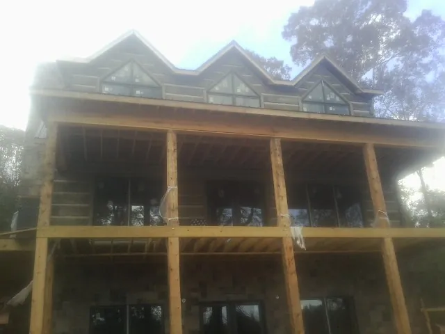 Dormers and porch framing on a large log home under construction — Roof Coating work by our crew in Mount Sidney