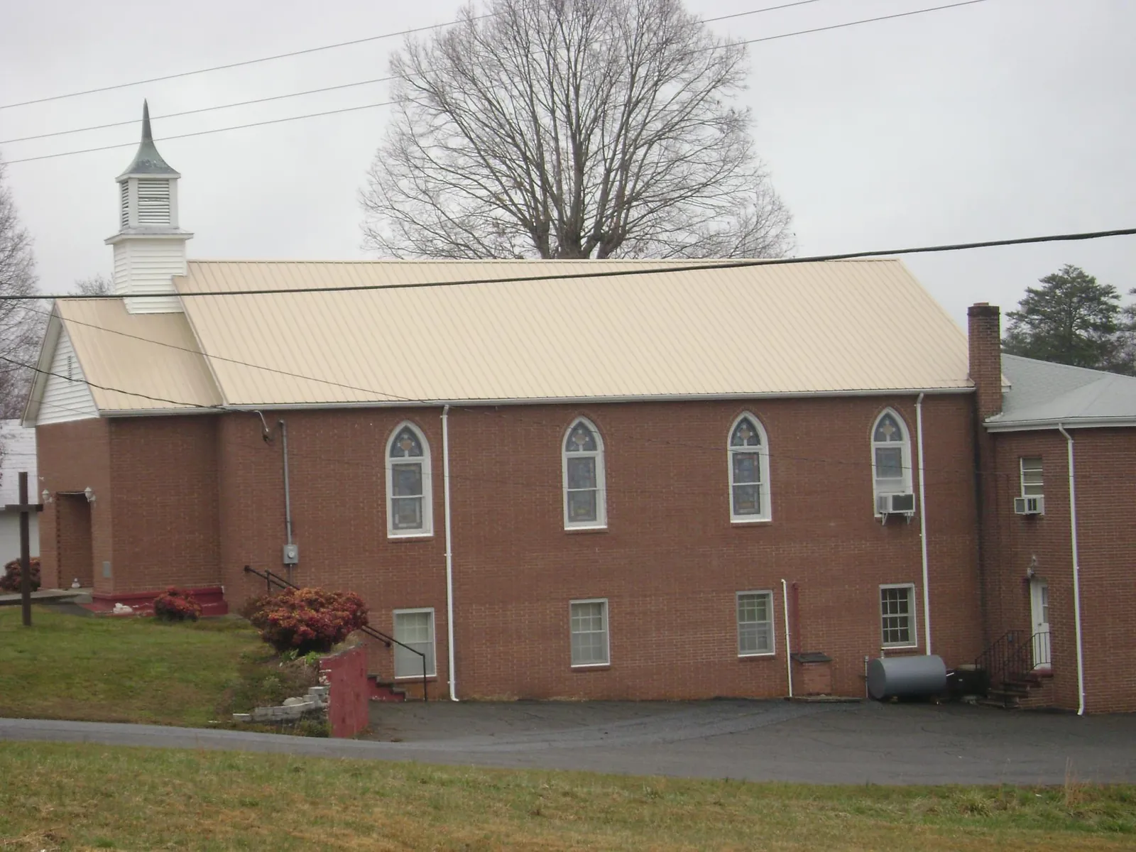 New tan metal roof on a brick church with a white steeple in Mount Sidney