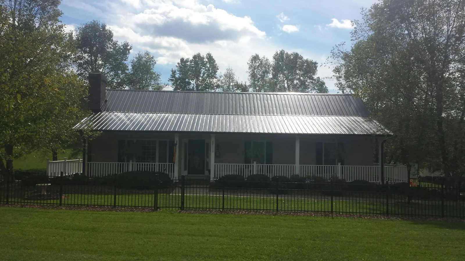 Gray metal roof on a brick ranch with a full width front porch — Gutter Guard Installation work by our crew in Mount Sidney