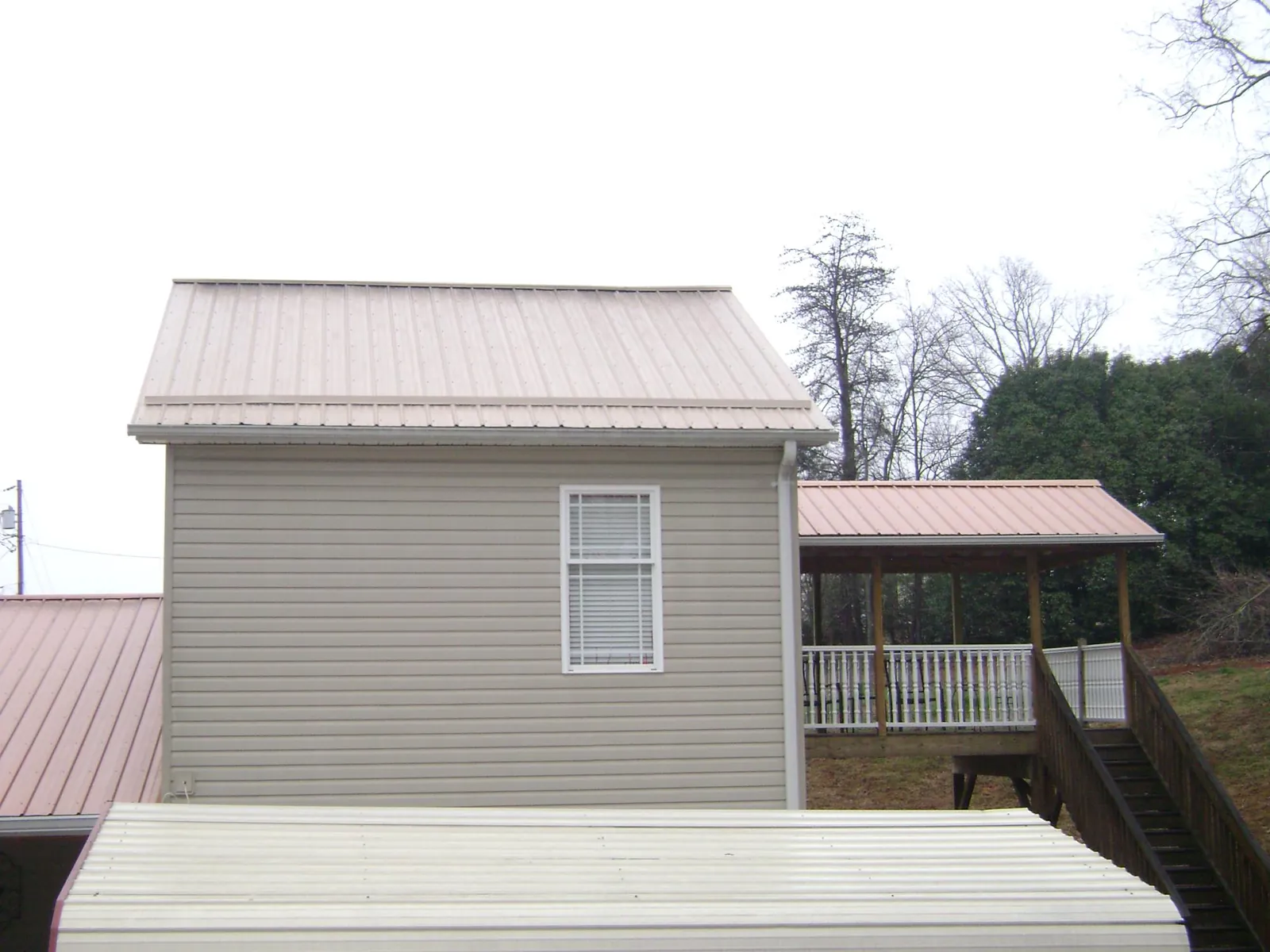 Tan metal roofs on a two story addition and attached porch, from a Roof Replacement job in Mount Sidney